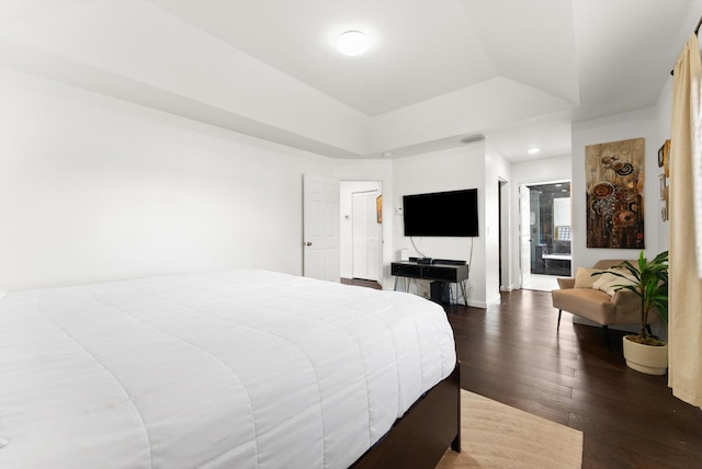 bedroom featuring dark hardwood / wood-style flooring, connected bathroom, and a raised ceiling