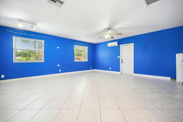 spare room featuring ceiling fan, an AC wall unit, light tile patterned flooring, and water heater