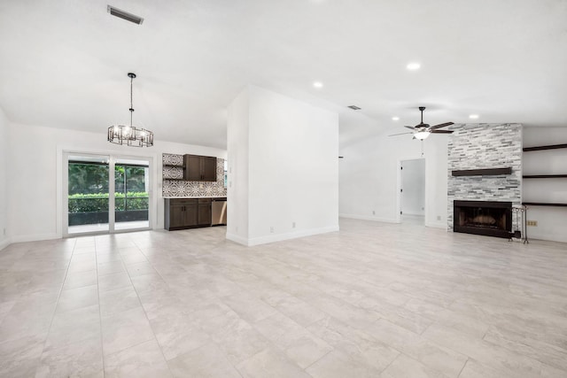 unfurnished living room featuring vaulted ceiling, ceiling fan with notable chandelier, and a fireplace