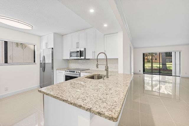 kitchen featuring appliances with stainless steel finishes, kitchen peninsula, light stone counters, sink, and white cabinetry