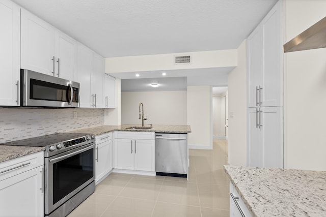 kitchen with white cabinetry, stainless steel appliances, sink, and light stone counters