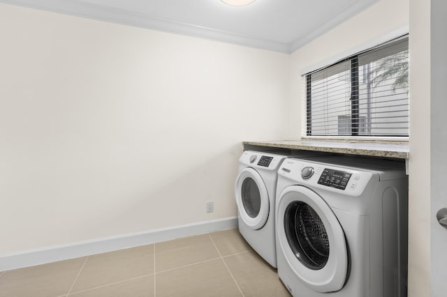 washroom with crown molding, washer and dryer, and light tile patterned floors