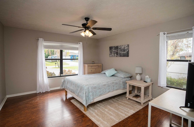 bedroom with dark hardwood / wood-style flooring, ceiling fan, and a textured ceiling