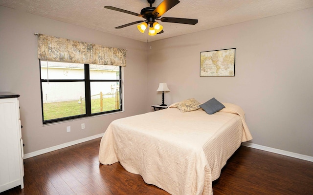 bedroom with ceiling fan, dark wood-type flooring, and a textured ceiling