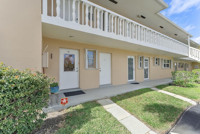 property entrance with a yard and stucco siding