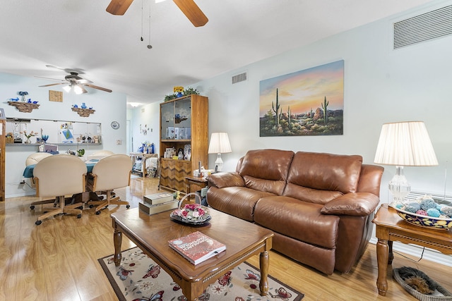 living room with light wood-type flooring, visible vents, and a ceiling fan