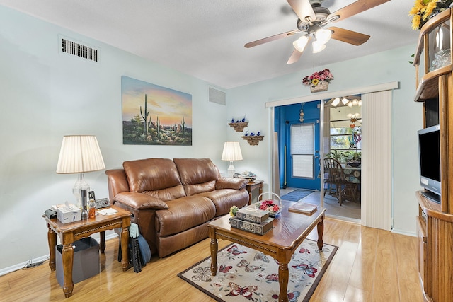 living room featuring a textured ceiling, light hardwood / wood-style floors, and ceiling fan