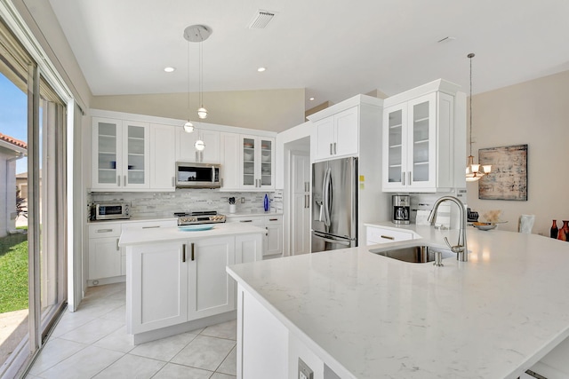 kitchen with appliances with stainless steel finishes, pendant lighting, lofted ceiling, sink, and a center island