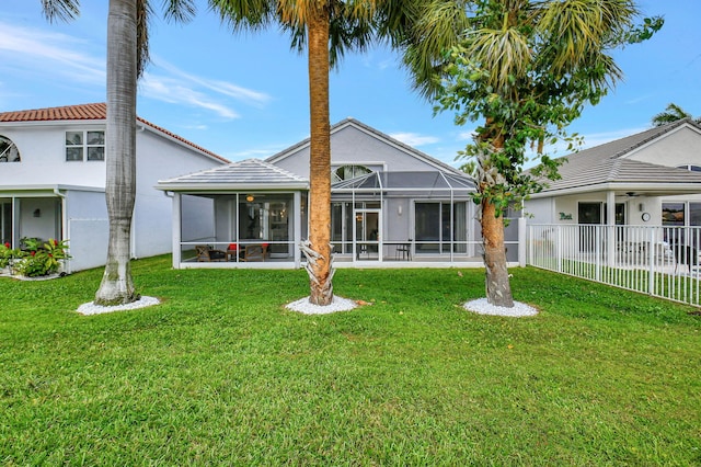 back of property with glass enclosure and a lawn