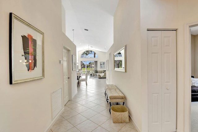 hall with high vaulted ceiling and light tile patterned floors