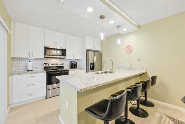 kitchen featuring appliances with stainless steel finishes, sink, white cabinets, and a kitchen breakfast bar