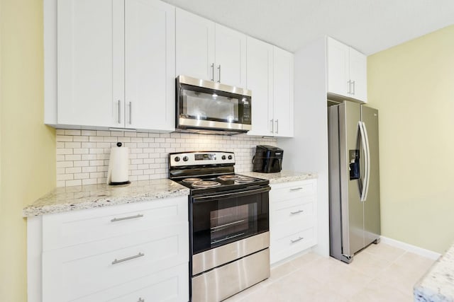 kitchen featuring white cabinets, decorative backsplash, light tile patterned floors, stainless steel appliances, and light stone countertops