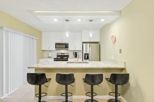 kitchen featuring white cabinets, a breakfast bar area, stainless steel appliances, sink, and backsplash