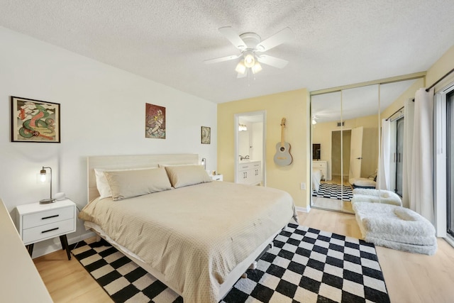 bedroom featuring connected bathroom, light hardwood / wood-style flooring, and a textured ceiling