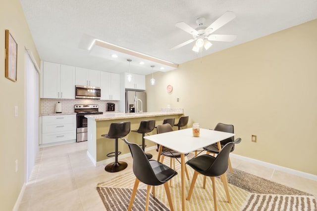 tiled dining room featuring ceiling fan and a textured ceiling