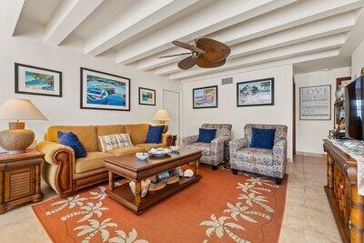 tiled living room with ceiling fan and beam ceiling