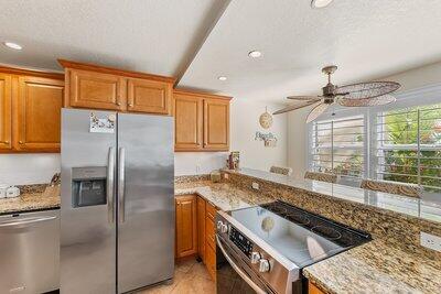 kitchen featuring ceiling fan, appliances with stainless steel finishes, light stone countertops, and kitchen peninsula