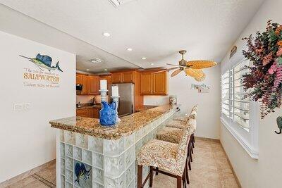 kitchen with ceiling fan, a breakfast bar, stainless steel fridge, and kitchen peninsula