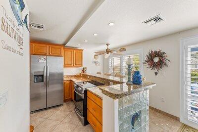 kitchen featuring electric stove, visible vents, stainless steel refrigerator with ice dispenser, and a peninsula