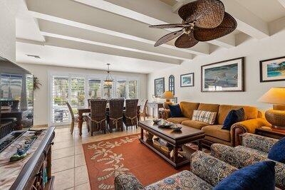 living area with light tile patterned floors, beamed ceiling, and a ceiling fan