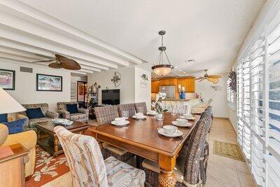 dining area featuring light tile patterned floors, ceiling fan, and beamed ceiling