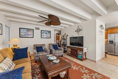 living area with a ceiling fan, beam ceiling, and light tile patterned floors