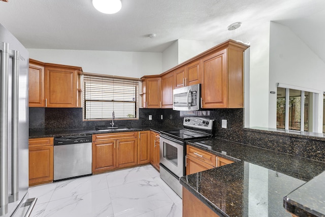 kitchen with sink, tasteful backsplash, a textured ceiling, dark stone counters, and stainless steel appliances