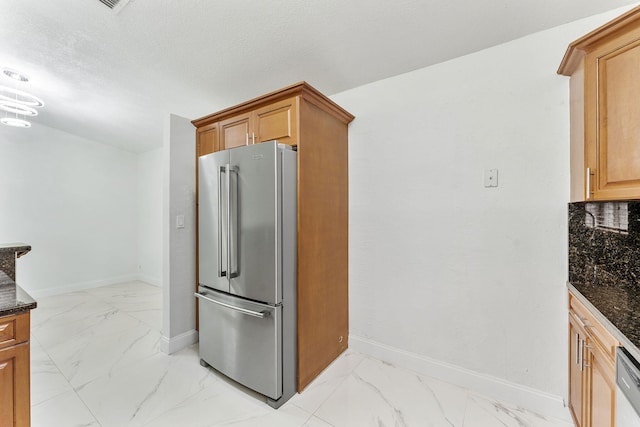 kitchen featuring dark stone countertops, high end refrigerator, and a textured ceiling