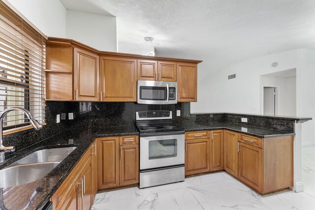 kitchen featuring appliances with stainless steel finishes, dark stone countertops, backsplash, and sink