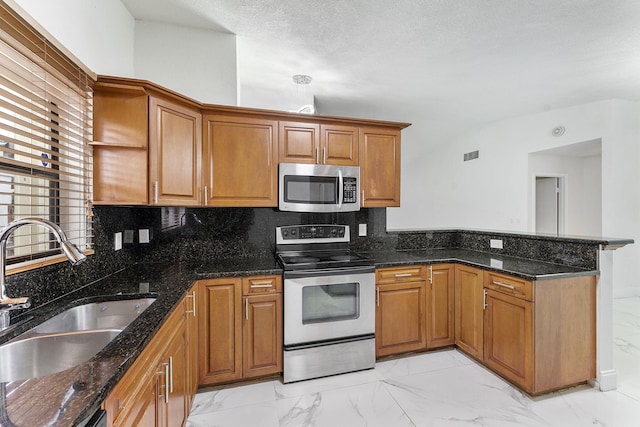 kitchen with tasteful backsplash, appliances with stainless steel finishes, sink, and dark stone countertops