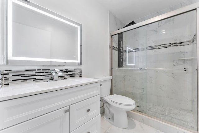 bathroom with vanity, backsplash, a shower with shower door, and toilet