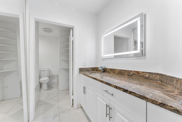 bathroom featuring vanity, toilet, and a textured ceiling