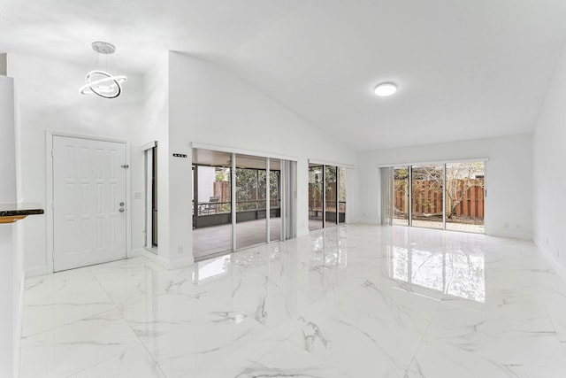 unfurnished living room featuring a notable chandelier, high vaulted ceiling, and plenty of natural light