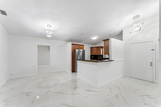 kitchen with lofted ceiling, stainless steel fridge, kitchen peninsula, and a textured ceiling