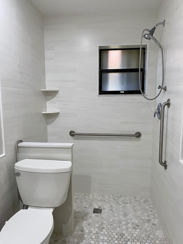 bathroom with a tile shower, tile walls, and toilet