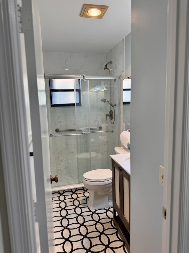 bathroom with vanity, a shower with shower door, and toilet