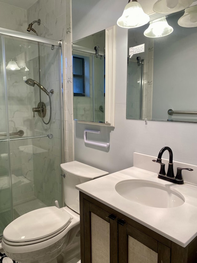 bathroom with a shower with door, vanity, and toilet