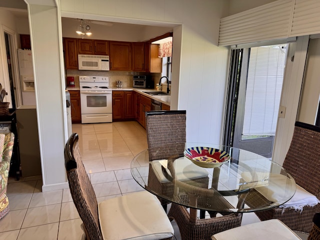 kitchen featuring light tile patterned flooring, white appliances, sink, and tasteful backsplash