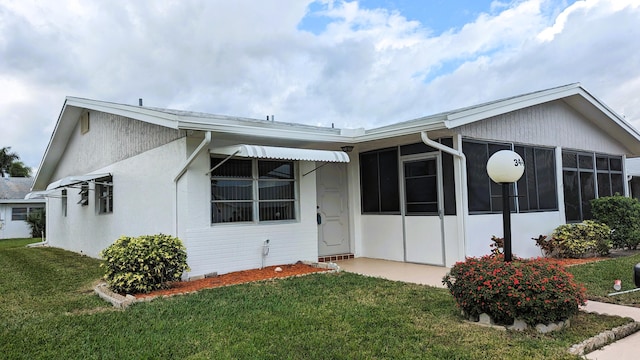 view of front of property featuring a front yard and a sunroom