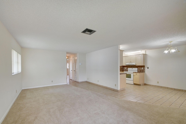 unfurnished living room with light colored carpet, a textured ceiling, and a chandelier