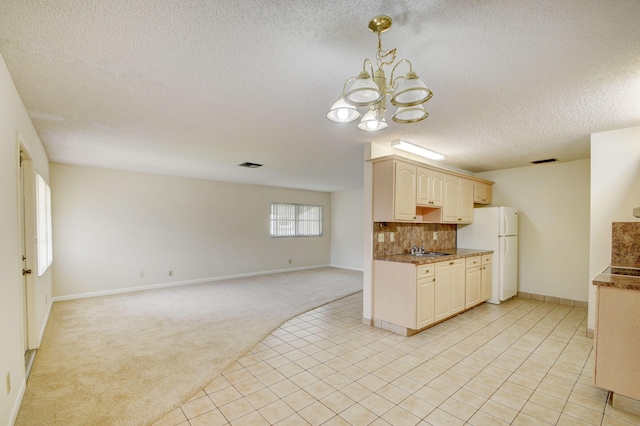 kitchen featuring backsplash, light carpet, an inviting chandelier, white refrigerator, and sink