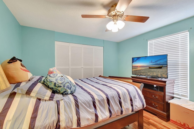 bedroom featuring light wood-type flooring, ceiling fan, and a closet