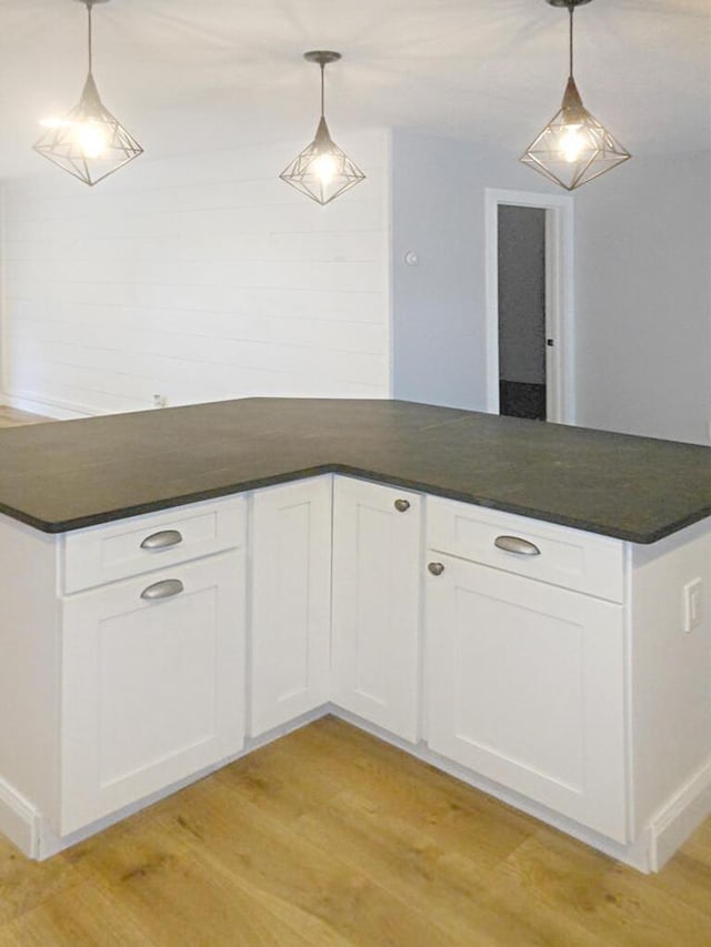 kitchen with white cabinetry, decorative light fixtures, and light hardwood / wood-style flooring