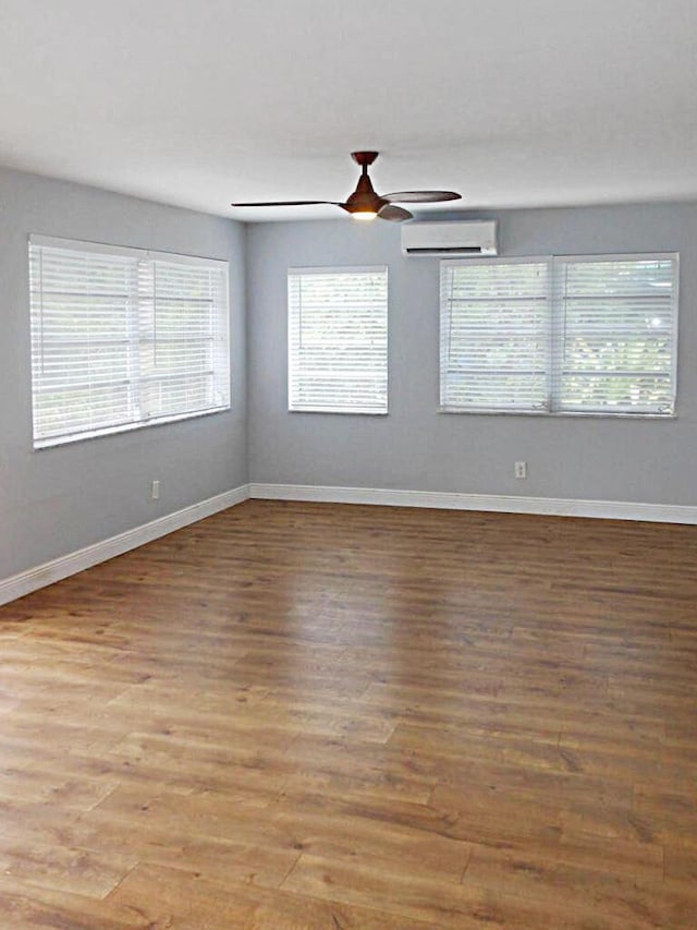 unfurnished room with wood-type flooring, an AC wall unit, and ceiling fan