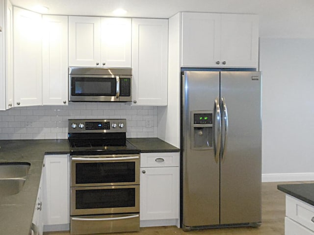 kitchen with white cabinetry, appliances with stainless steel finishes, backsplash, and light hardwood / wood-style flooring