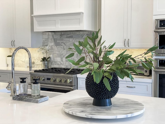 kitchen with white cabinets, decorative backsplash, stainless steel appliances, and custom range hood