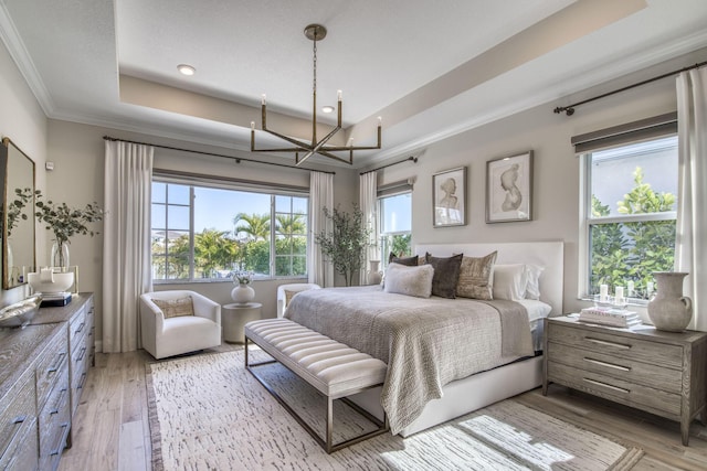 bedroom featuring a raised ceiling, light wood-type flooring, and ornamental molding