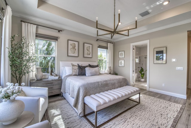 bedroom with hardwood / wood-style flooring, connected bathroom, a tray ceiling, and ornamental molding