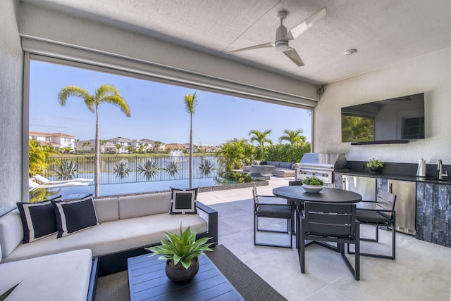 view of patio with ceiling fan, sink, grilling area, a water view, and an outdoor hangout area