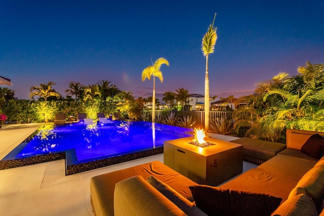 pool at dusk featuring pool water feature, an outdoor living space with a fire pit, and a patio area